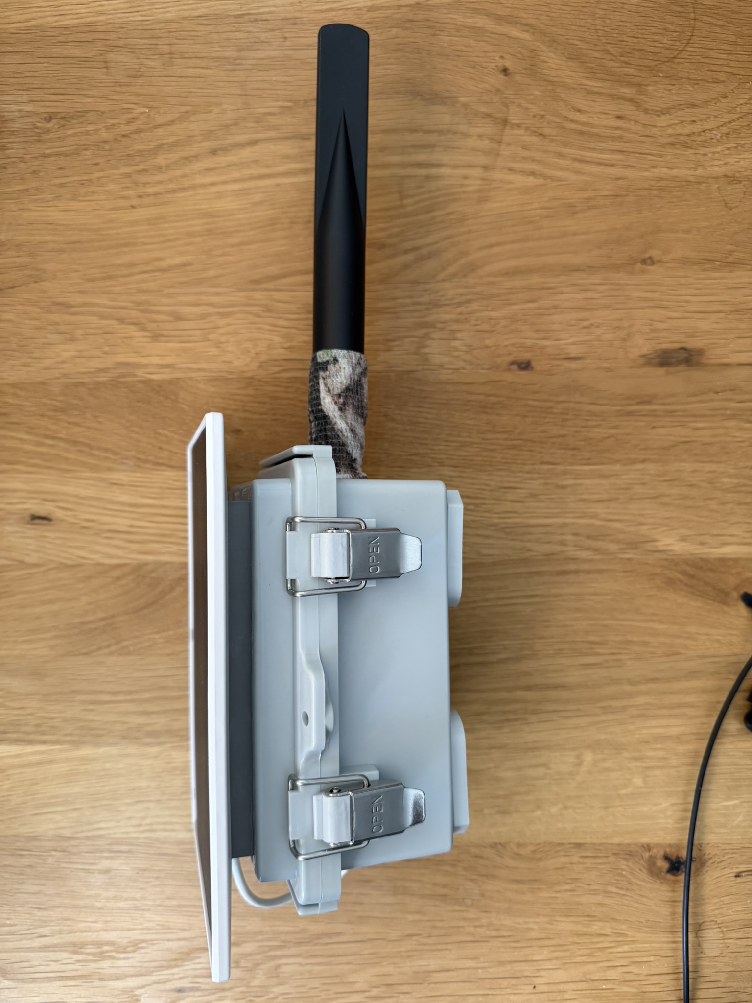 Sealed enclosure from the side: weatherproof IP-rated box with stainless steel clasps, solar panel mounted flat, and the ALFA antenna at the top — ready for outdoor deployment